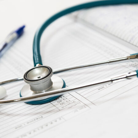 A clinician's stethoscope laying on top of bronchiectasis diagnostic test paperwork.
