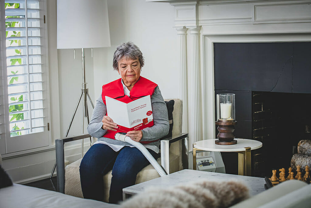 Older woman reading SmartVest manual while wearing vest.