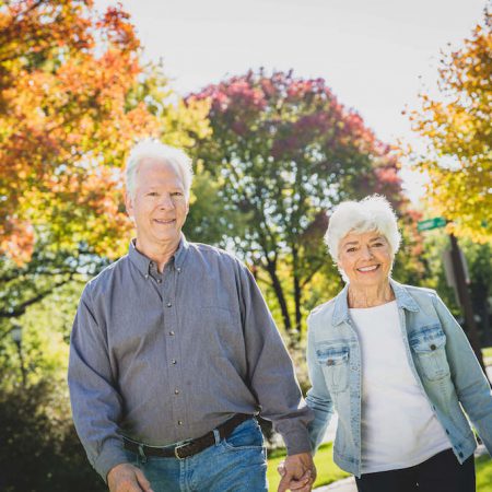 An older couple holds hands while walking outdoors