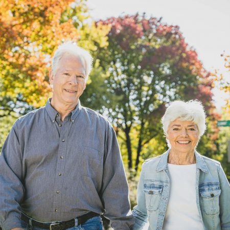 An older couple holds hands while walking outdoors