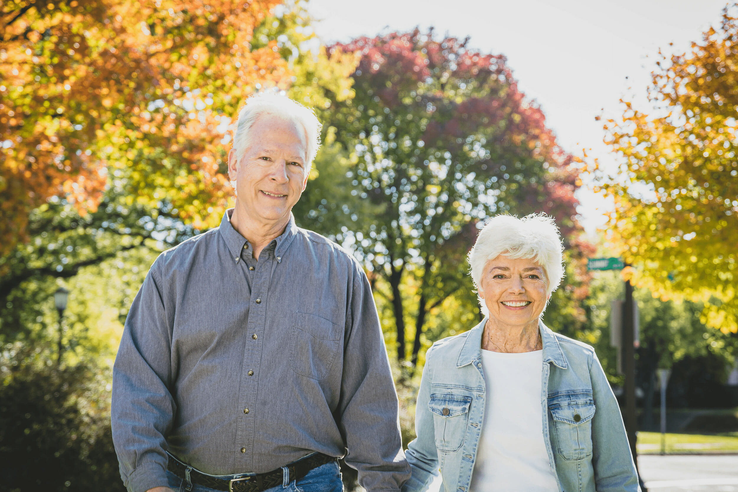 An older couple holds hands while walking outdoors