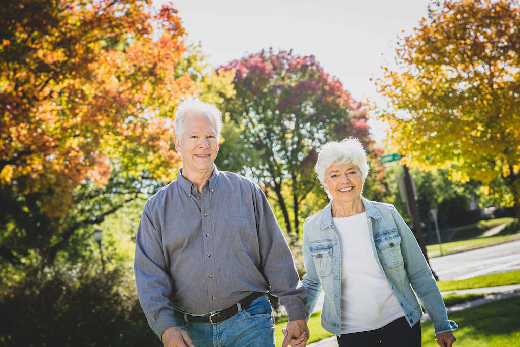 An older couple holds hands while walking outdoors