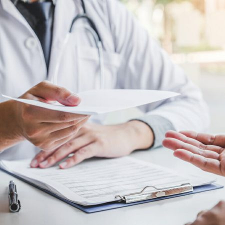 A doctor hands a prescription to a patient