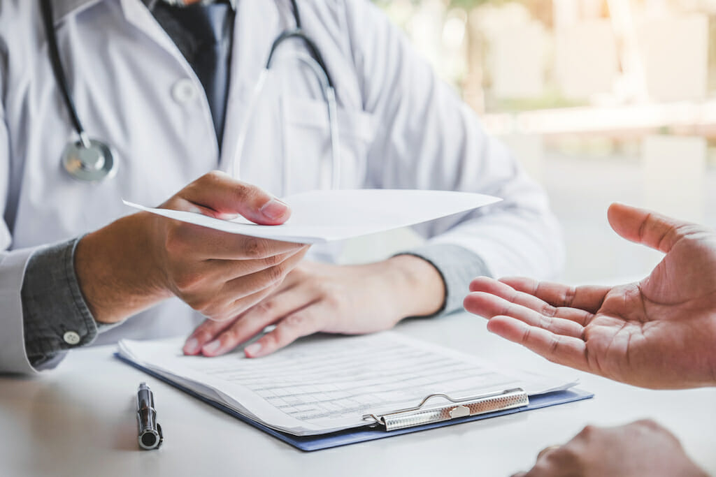 Doctor sitting with patient. Doctor passes prescription for SmartVest to patient.
