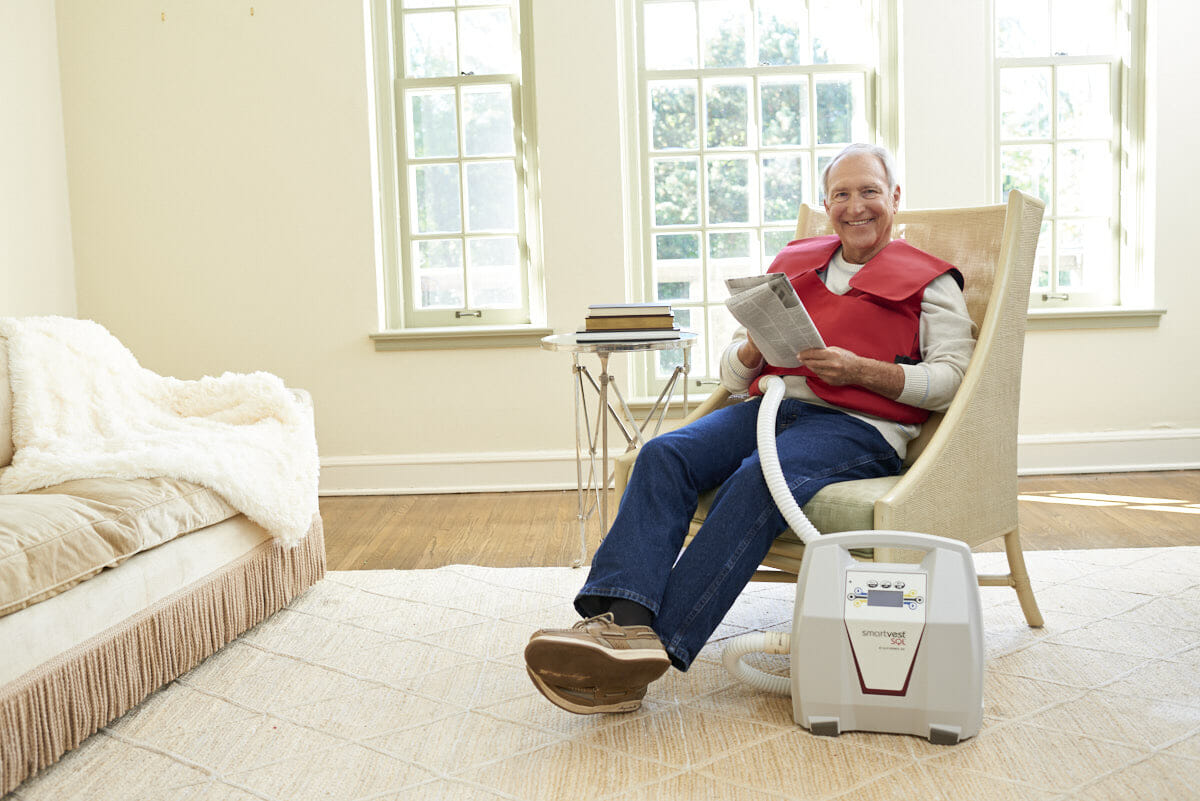 A man relaxes with a newspaper during his SmartVest therapy
