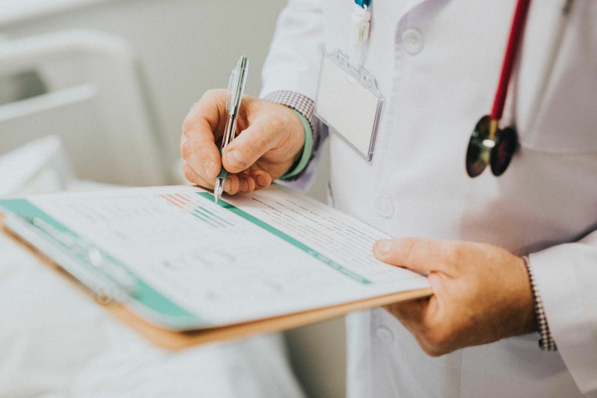 A doctor reviews their clipboard of patient details