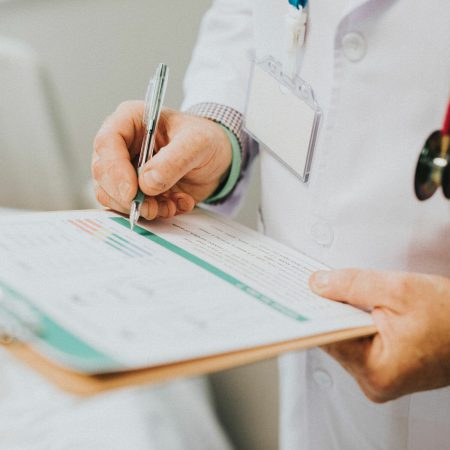 A doctor reviews their clipboard of patient details