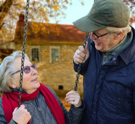 A woman is greeted by her husband while she is on a swing