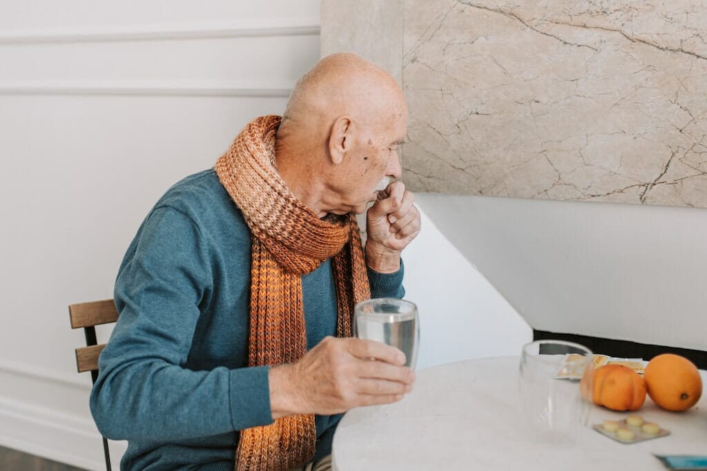 Older man coughing into hand.