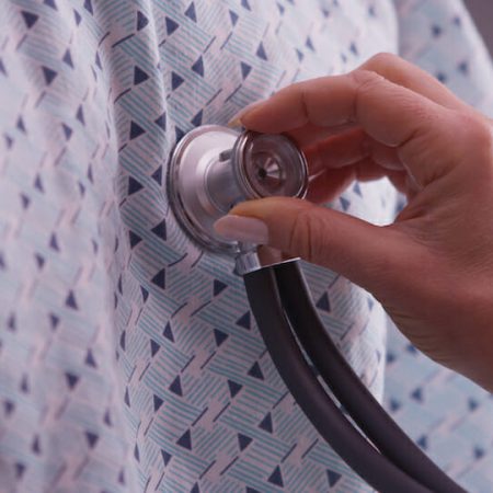 A doctor presses their stethoscope to the chest of a patient