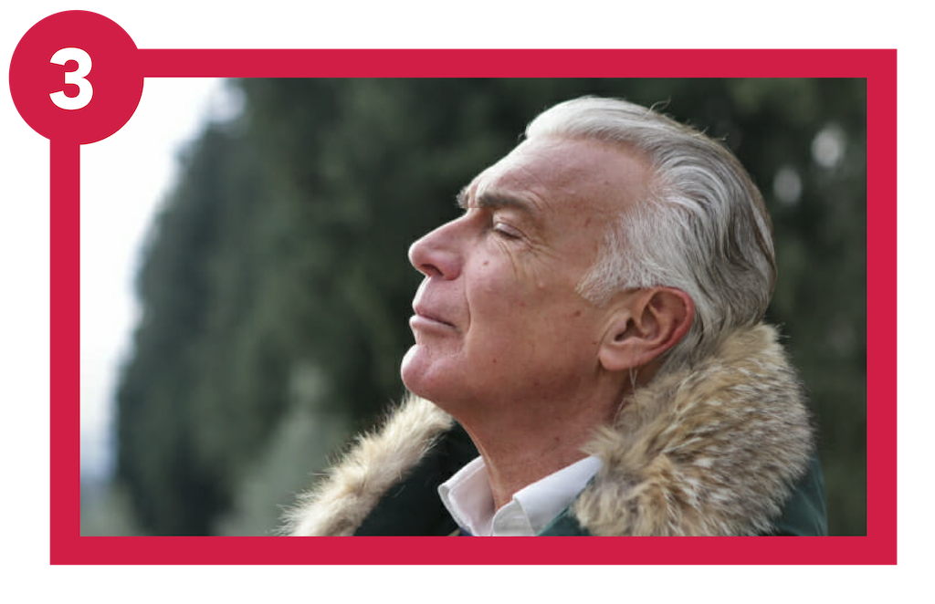 Older man breathing deeply outside.