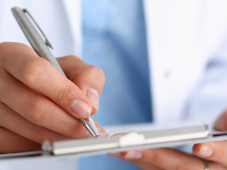A doctor takes notes on a clipboard
