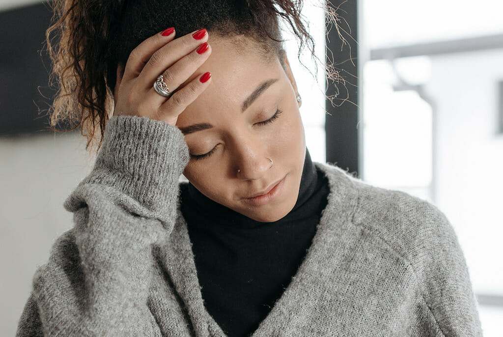Young woman living with COPD holding head from fatigue-like symptoms.
