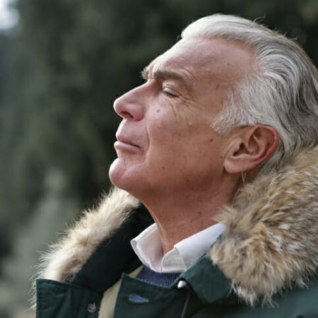 A man inhales deeply through his nose while outdoors