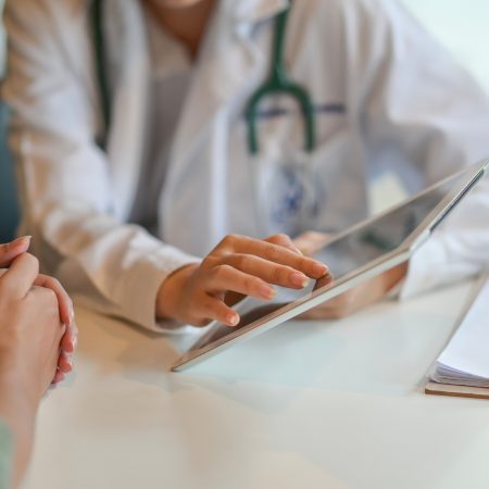 A doctor uses a tablet to explain something to a patient