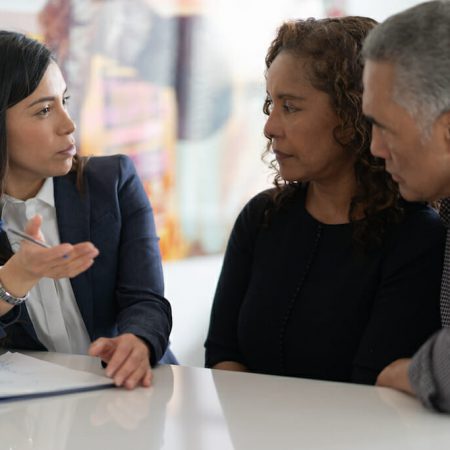 A professionally dressed woman talks to a husband and wife