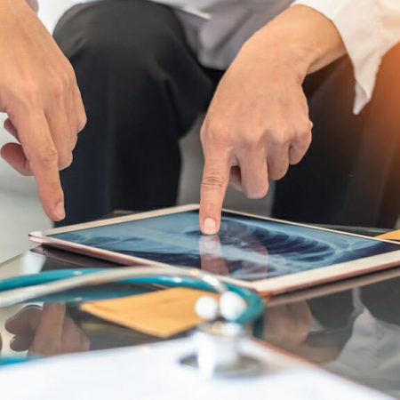 A couple uses a tablet to examine an x-ray of a torso