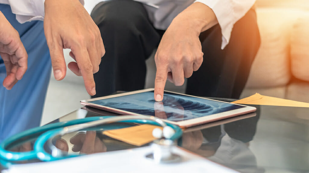 Doctor and patient looking at 3D image of lungs on iPad.