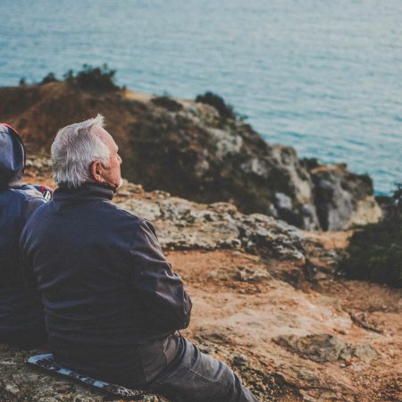 A couple sits on a rocky shoreline