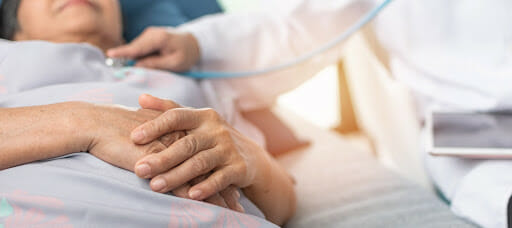 COPD patient laying in hospital bed with doctor checking breathing.