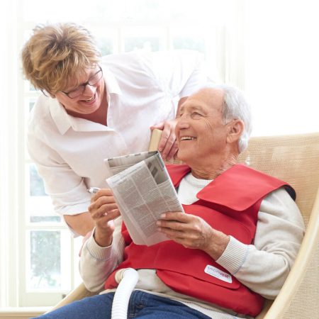 A woman leans over to greet a man while he is doing his SmartVest session
