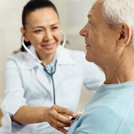 Clinician using stethoscope to hear lungs in patient's chest.