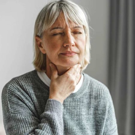 Woman feeling her throat muscles as she begins huff coughing after airway clearance therapy.
