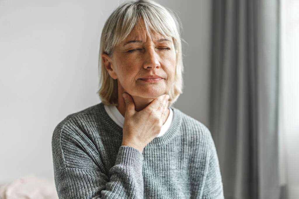 Woman feeling her throat muscles as she begins huff coughing after airway clearance therapy.