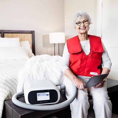 SmartVest user sitting on bed while using airway clearance device.