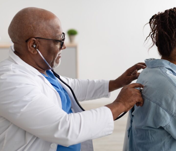 Doctor listening to patient's congested lungs using a stethoscope.