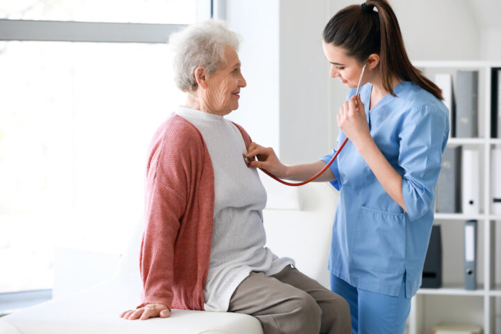 Older woman with COPD getting lungs checked in clinician office.
