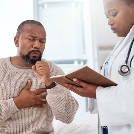 Older man experiencing reaction to airway obstruction while talking to clinician.