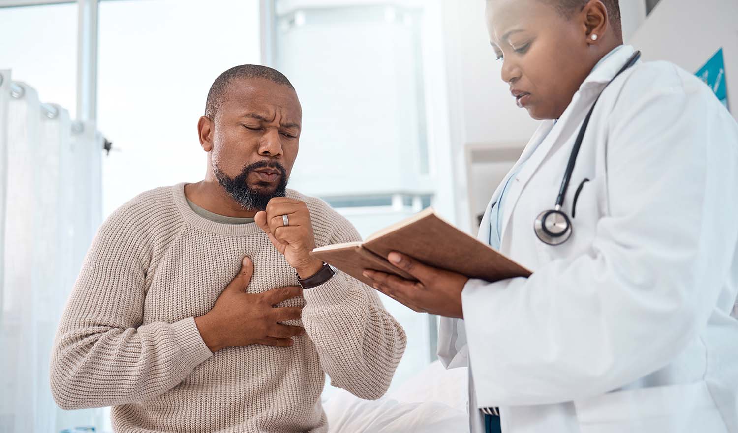 Older man experiencing reaction to airway obstruction while talking to clinician.