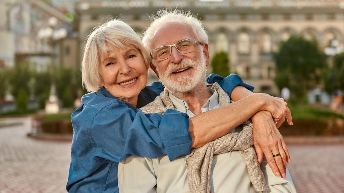 Senior couple hugging and smiling.