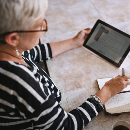 Woman looking at article on tablet about cystic fibrosis vs pulmonary fibrosis.