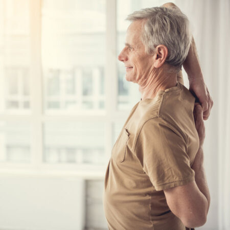 Older man stretching his arms and back for good posture.