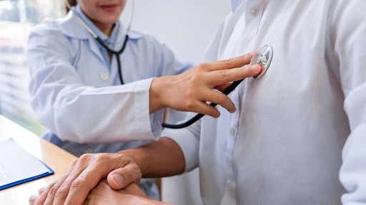 Doctor holding up stethoscope to a patient's chest to check airways.