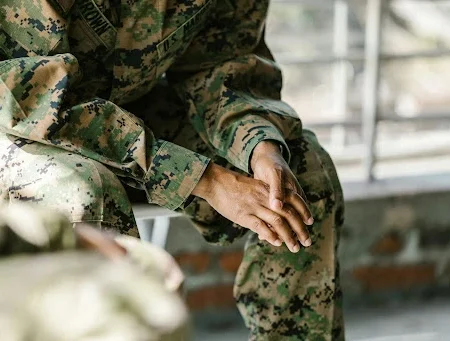 Veterans with cystic fibrosis. Veteran in fatigue sitting down and leaning over with hands together.