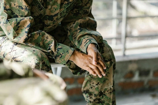 Veterans with cystic fibrosis. Veteran in fatigue sitting down and leaning over with hands together.