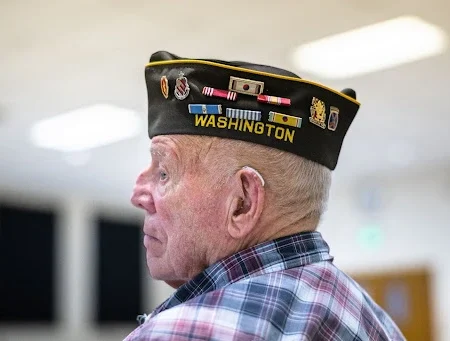 Veteran wearing decorated military hat.